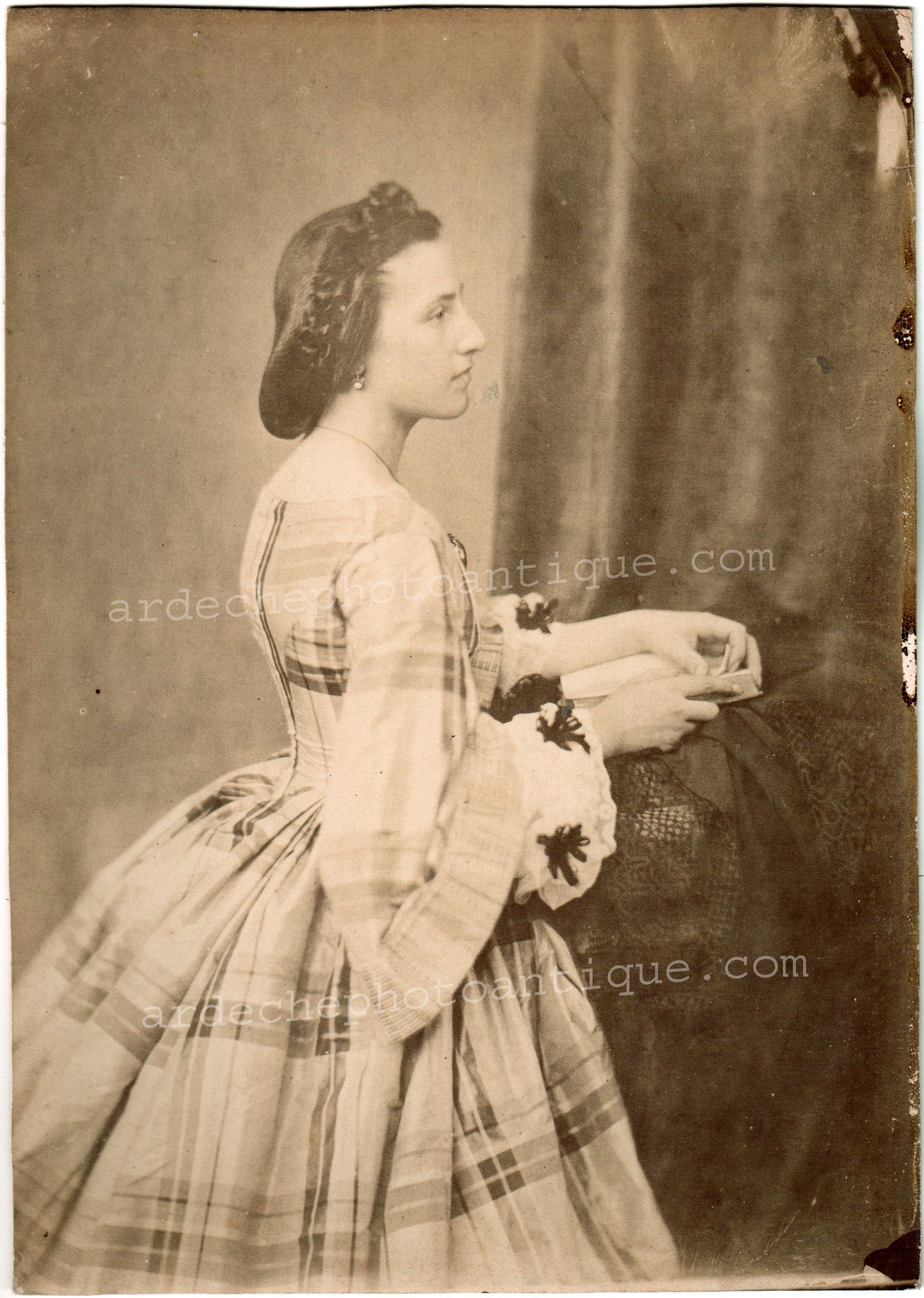 Jean-Baptiste Frénet (1814-1889).Photographie, 1855-1862, Portrait de profil d'une belle femme à la robe élégante et bien et à belle coiffe, au regard doux et inocent, tenant dans ses mains un ouvrage. Tirage sur papier Albuminé, format 16x22,5 cm