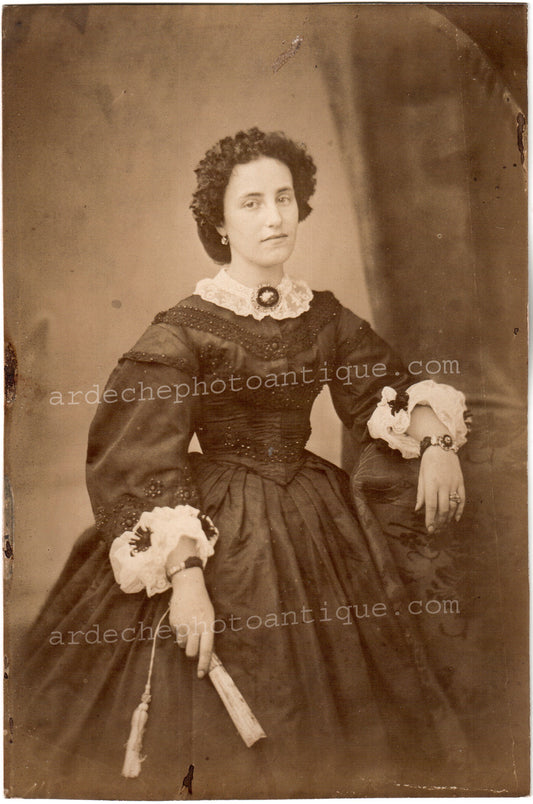 Jean-Baptiste Frénet (1814-1889).Photographie. Portrait de trois quart d'une belle jeune femme aux nombreux bijoux et à la tête inclinée, un regard serein, tenant dans sa main droite un éventail, c 1855-1862. Tirage sur papier albuminé, format 15x22,5cm